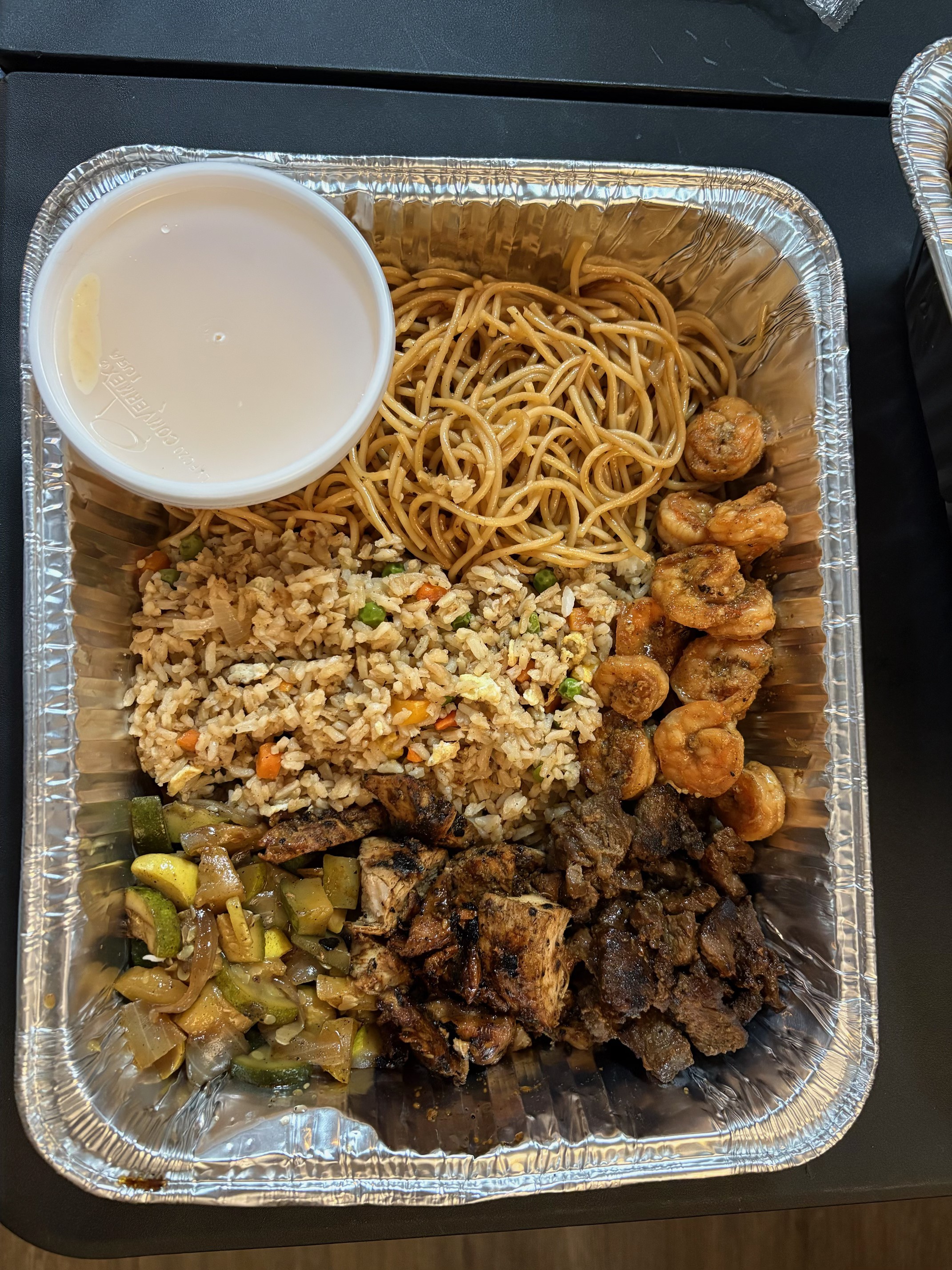 Hibachi tray with shrimp, steak, chicken, fried rice, noodles, and veggies